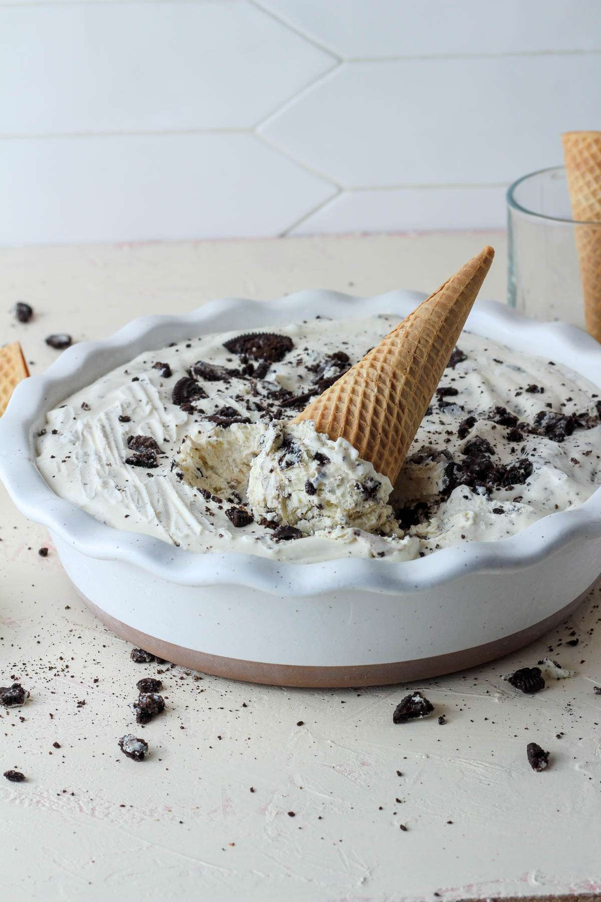 A white pie pan with vegan cookies and cream ice cream with a sugar cone sticking up out of the ice cream.