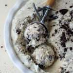 A close up of two scoops of vegan no churn cookies and cream ice cream in a white pie pan.
