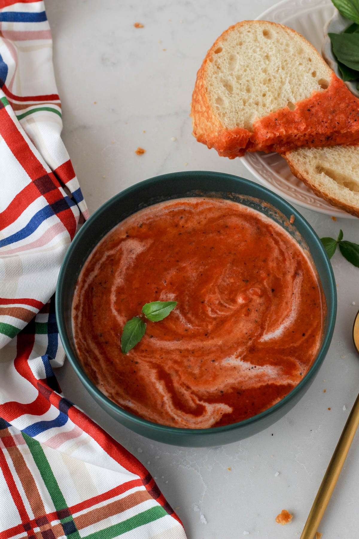 A green bowl filled with gluten-free and dairy-free tomato soup with a swirl of full fat coconut milk.