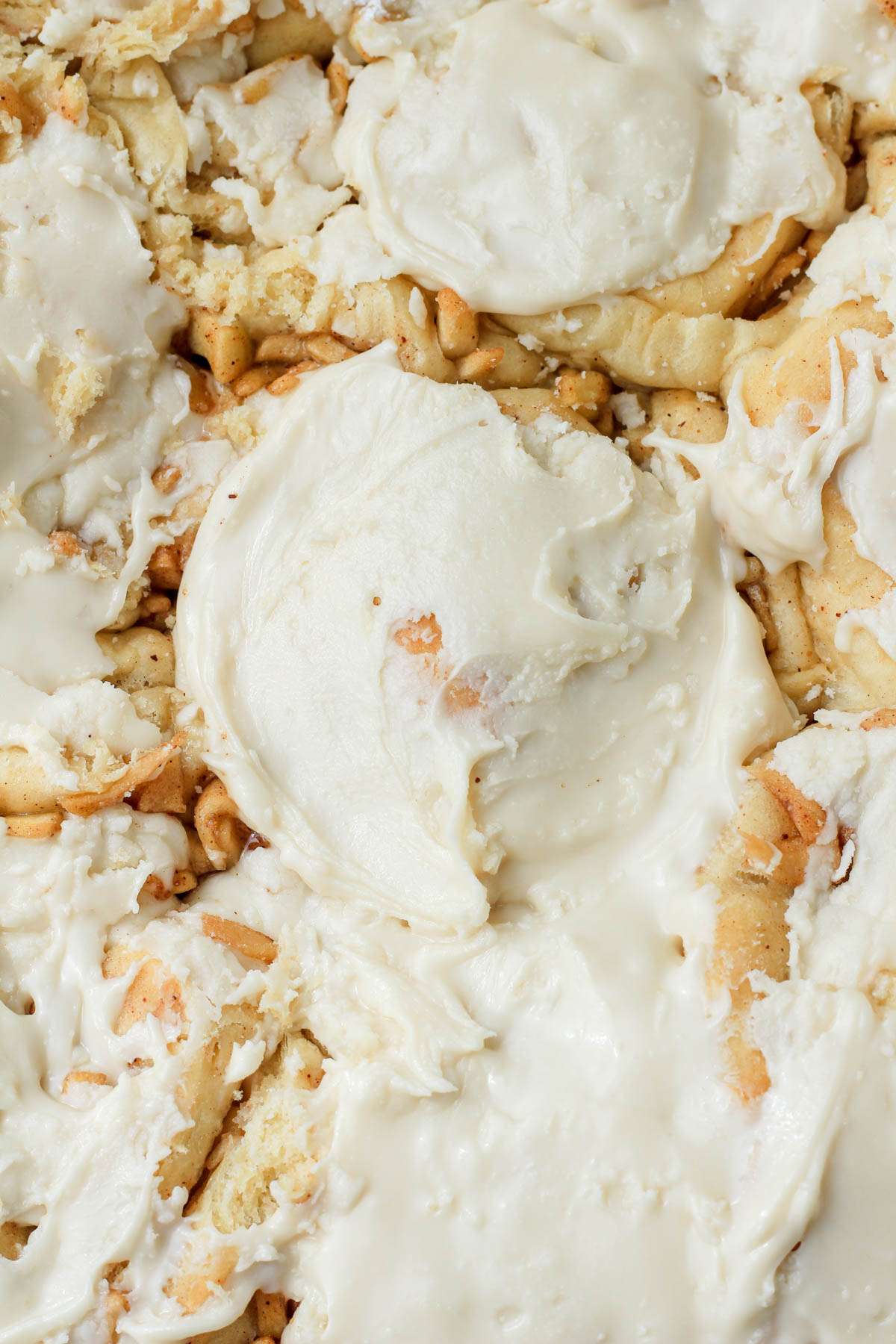 The center of a pan of apple pie cinnamon rolls with maple icing.