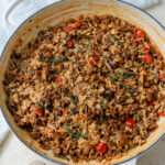 A white skillet of dairy-free chorizo and mushroom risotto on a cream counter.