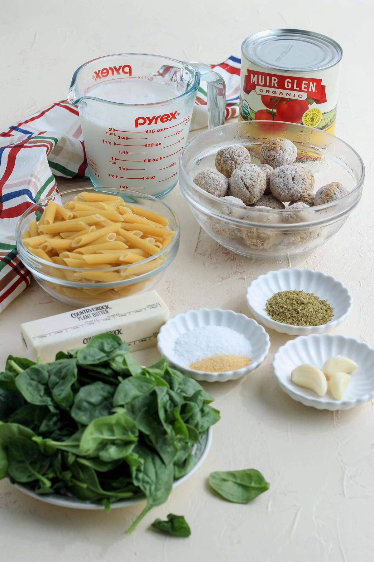 Ingredients for dairy-free baked penne with meatballs on a cream counter.