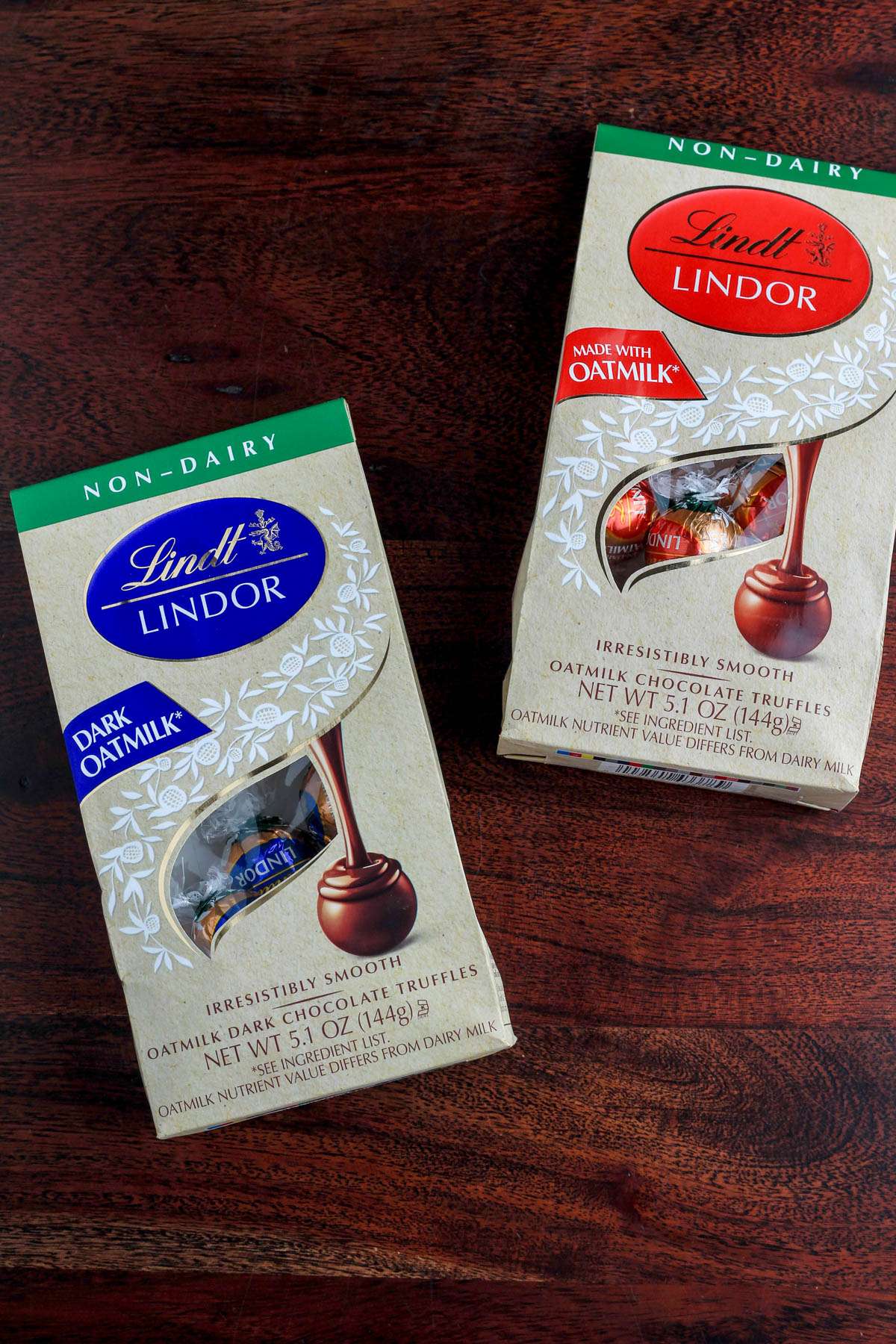 A wooden table with two packages of non-dairy Lindt Truffles.