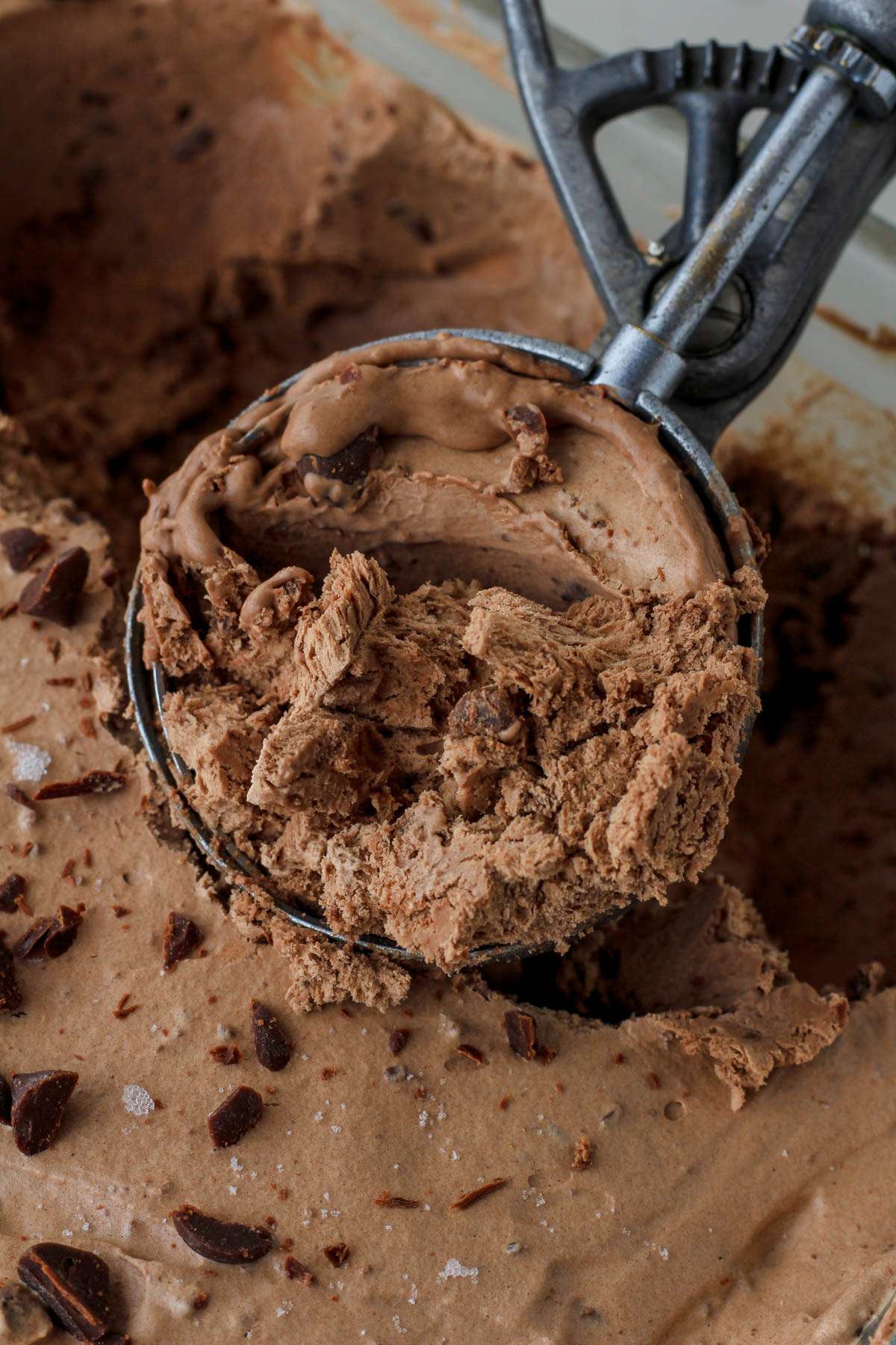 An ice cream scoop with a large scoop of vegan no churn chocolate chocolate chip ice cream.