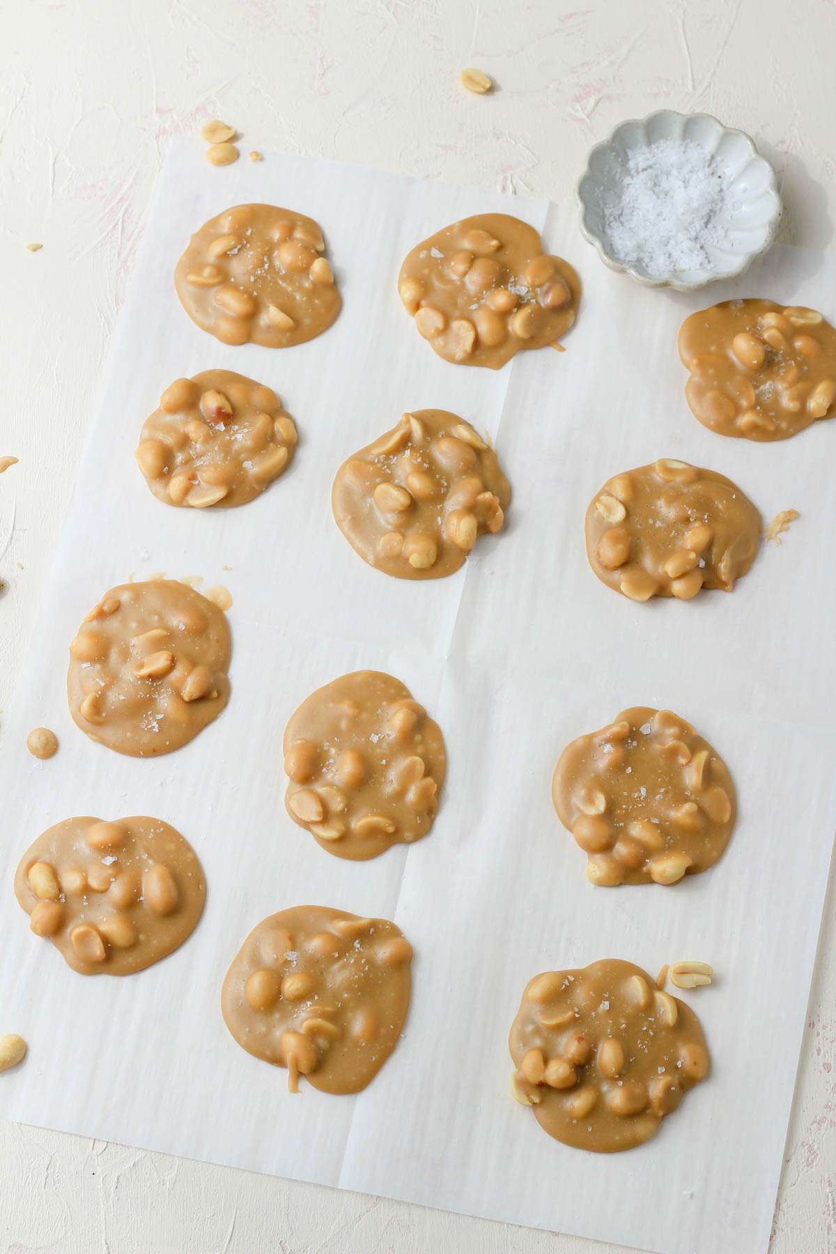 A parchment paper covered in peanut pralines after cooling.