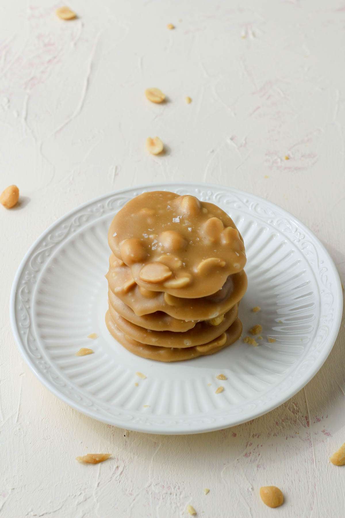 A tower of five vegan peanut pralines on a white plate on a cream counter.