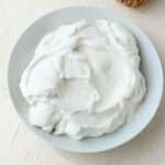 A white bowl filled with vegan pumpkin spice whipped cream on a cream counter.