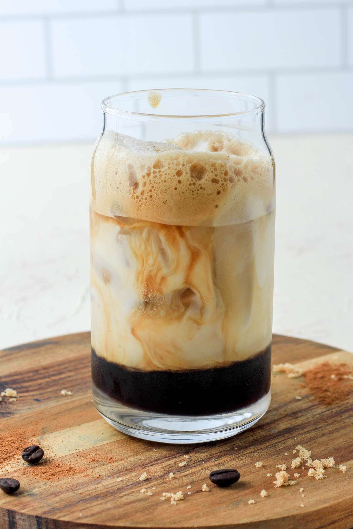 A close up of a brown sugar oat milk espresso in a glass cup after pouring oat milk in.