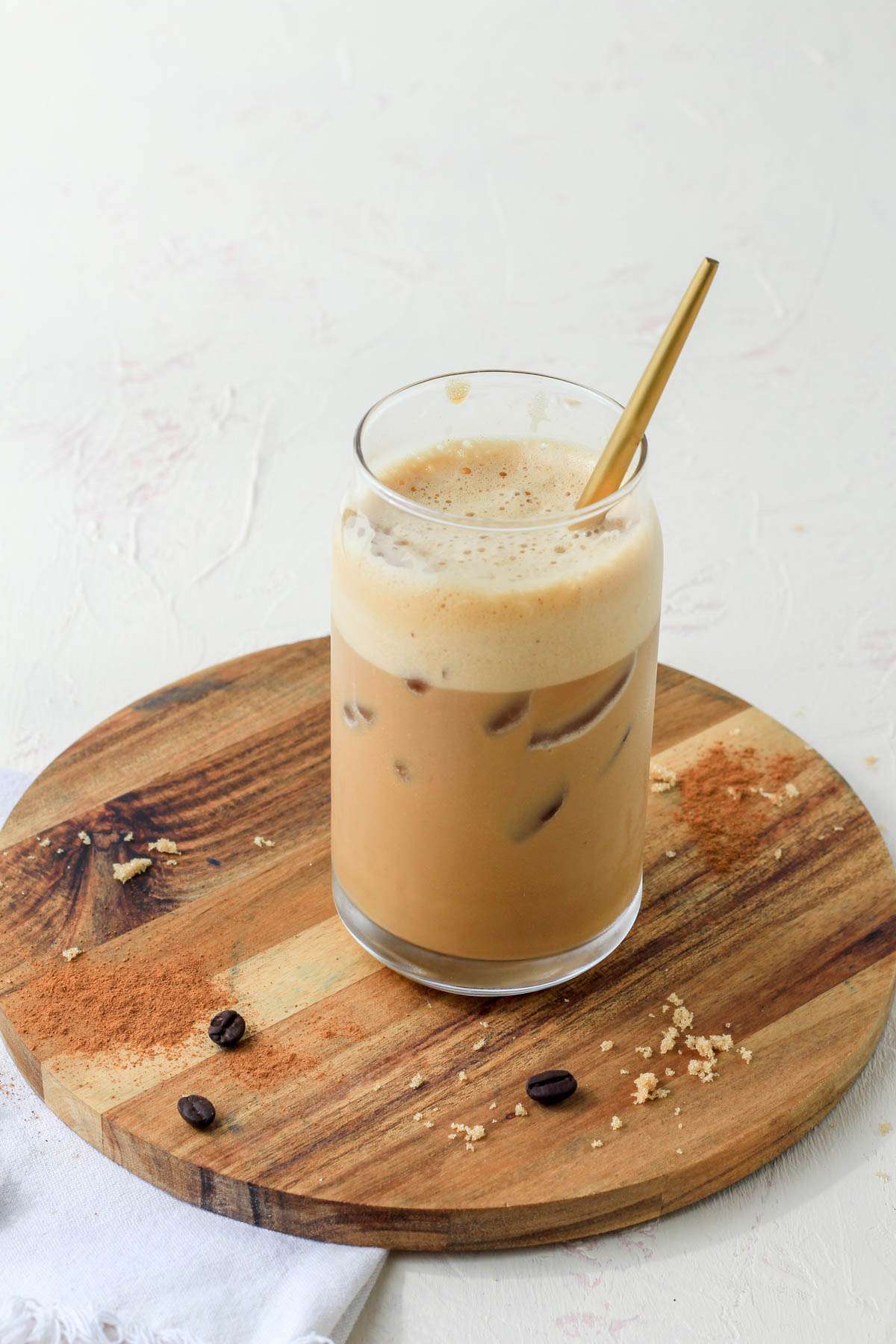 A glass cup with a homemade brown sugar oat milk shaken espresso with a gold spoon.