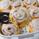 A close up of a dairy-free pumpkin spice cinnamon roll on a cake server.