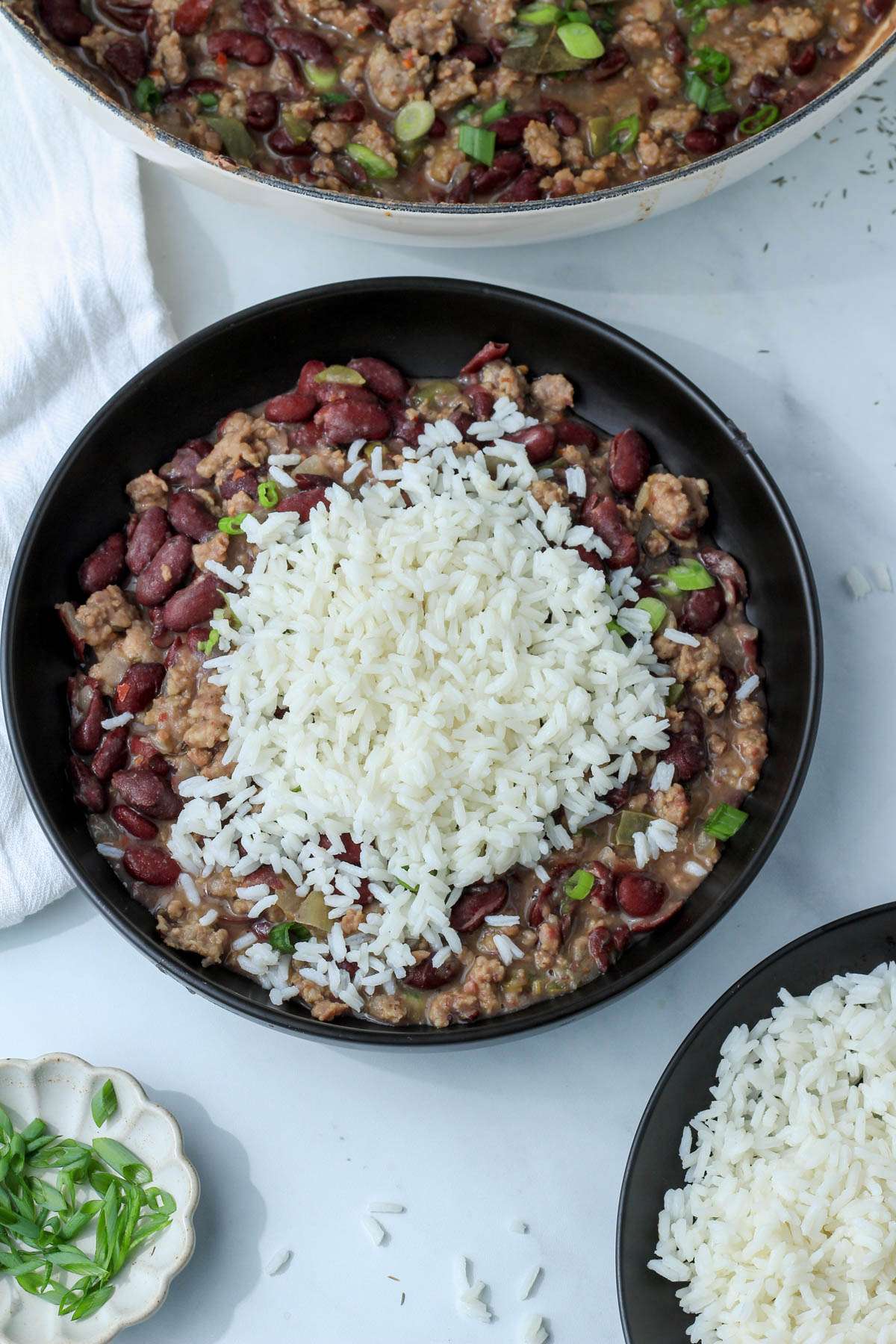 A black bowl of red beans and rice on a white counter.