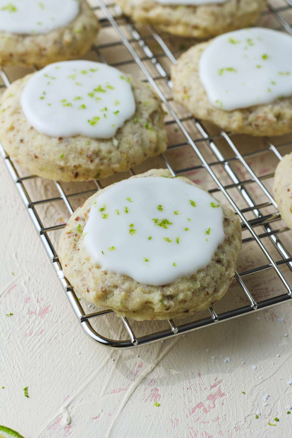A soft lime cookie on a cooling rack topped with lime zest.