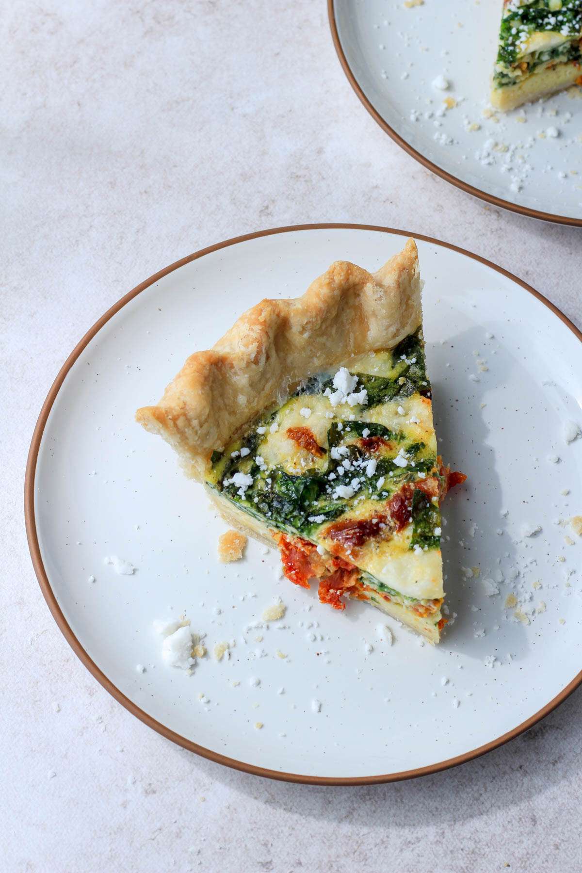 A top down picture of a plate with a slice of quiche.