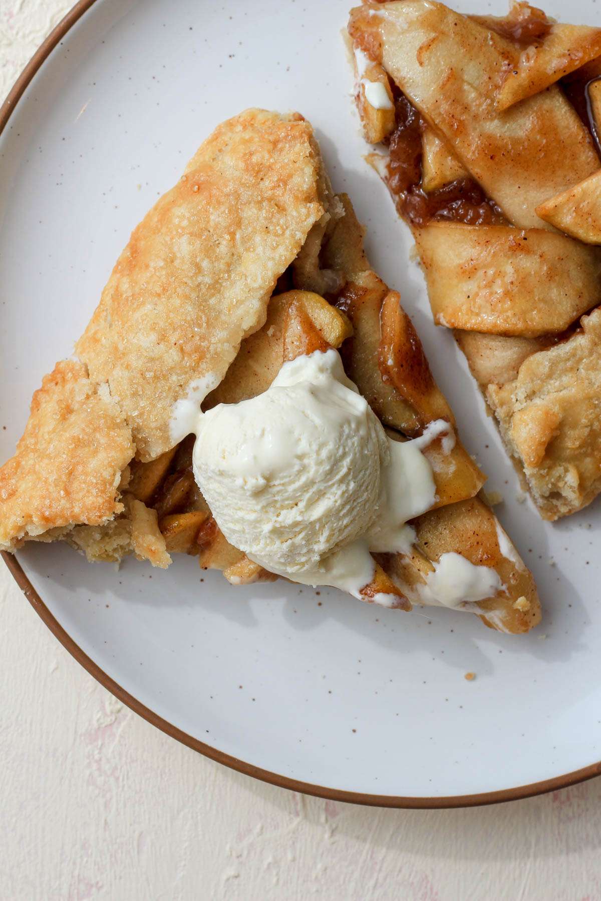 A white plate with a brown rim topped with two slices of dairy-free apple galette.