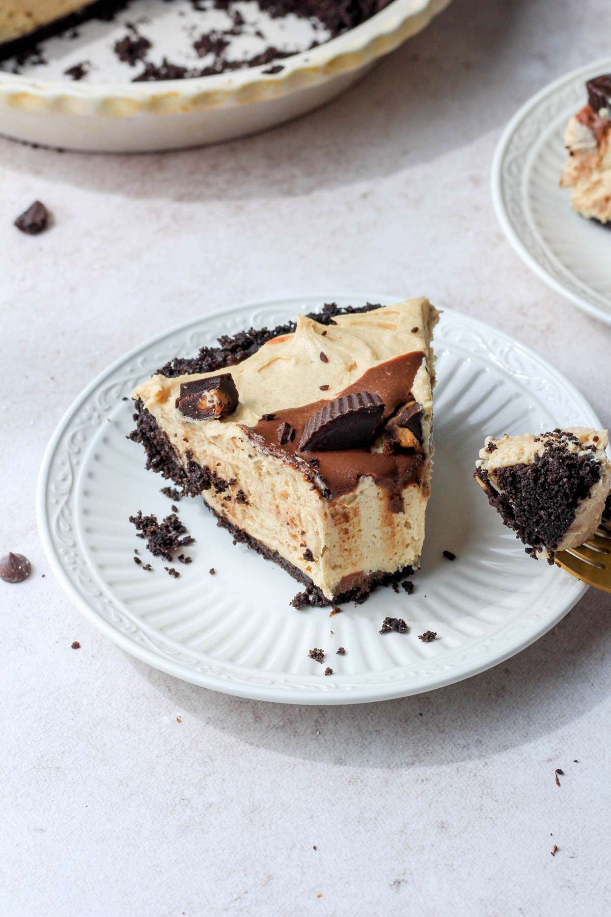 A small white plate with a slice of no bake peanut butter pie with a bite taken out.