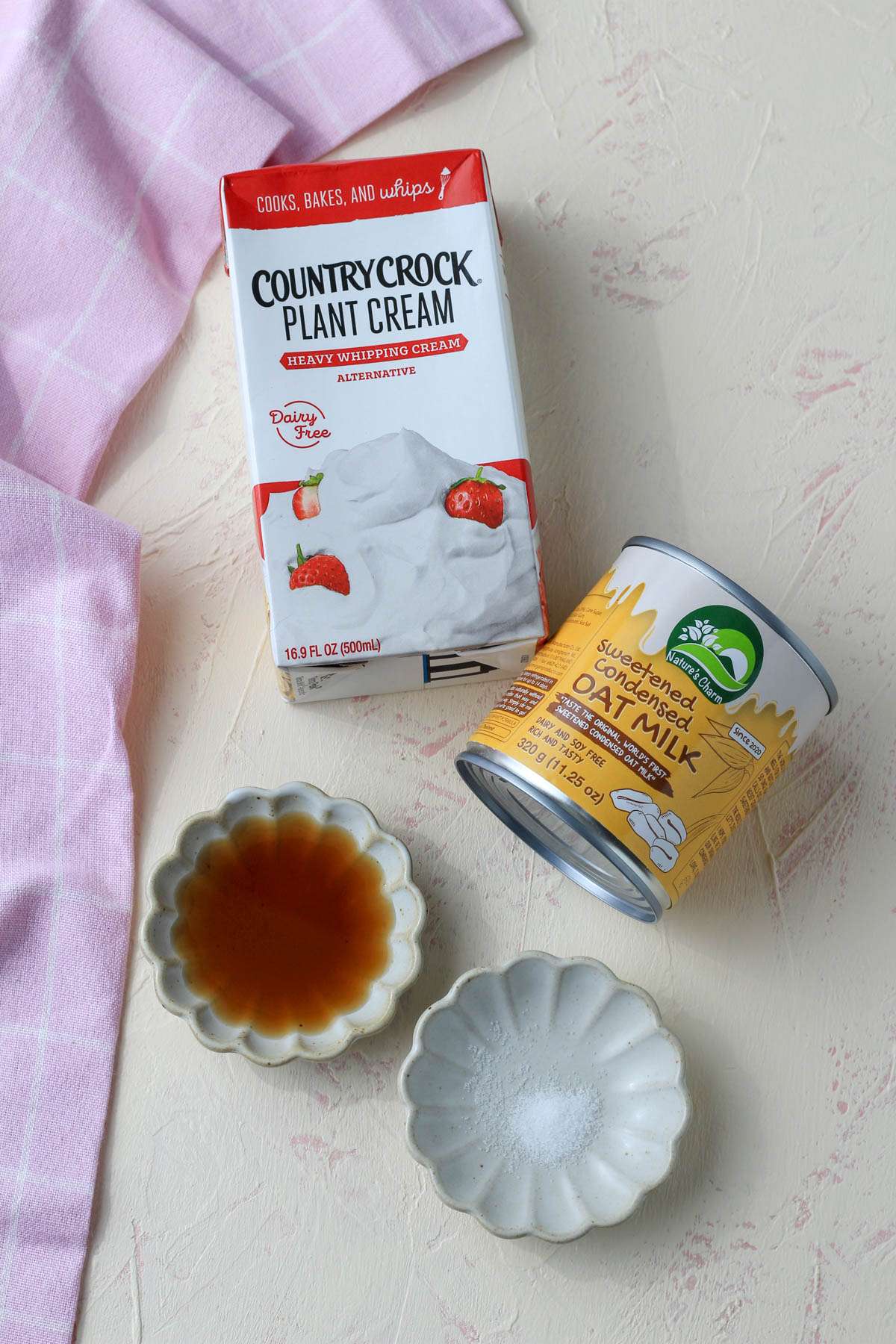 Ingredients for vegan no churn vanilla ice cream on a cream counter with a pink towel.