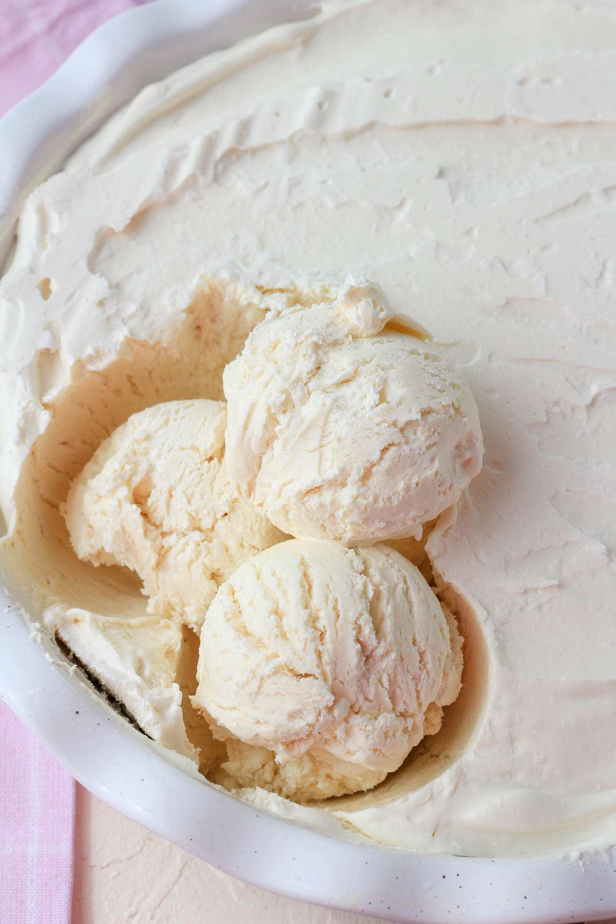 A white pan with vegan no churn vanilla ice cream scooped into three scoops on the left.