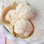 A close up of three scoops of vegan vanilla ice cream in a white pan.