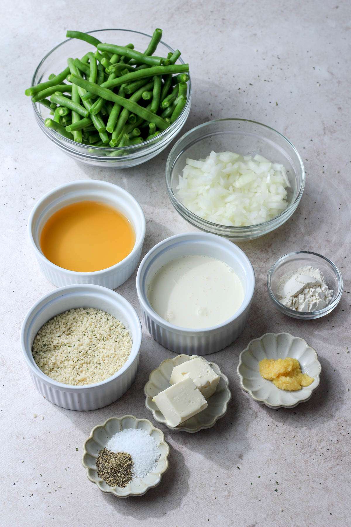 Ingredients for dairy-free green bean casserole in separate bowls and dishes.