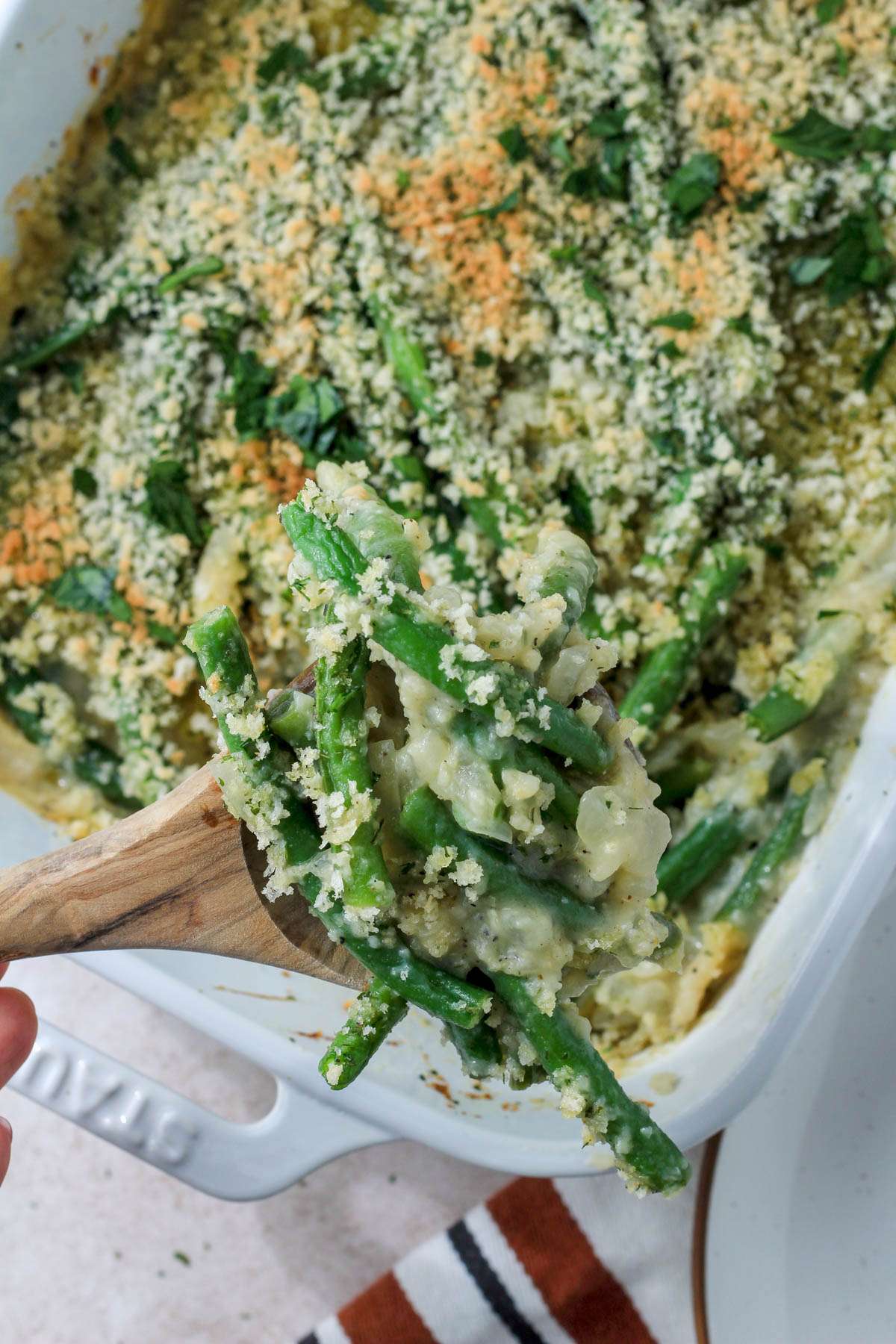 A wooden spoon topped with a scoop of homemade green bean casserole without any dairy.