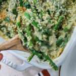 A close up of a spoonful of vegan green bean casserole over the casserole dish.