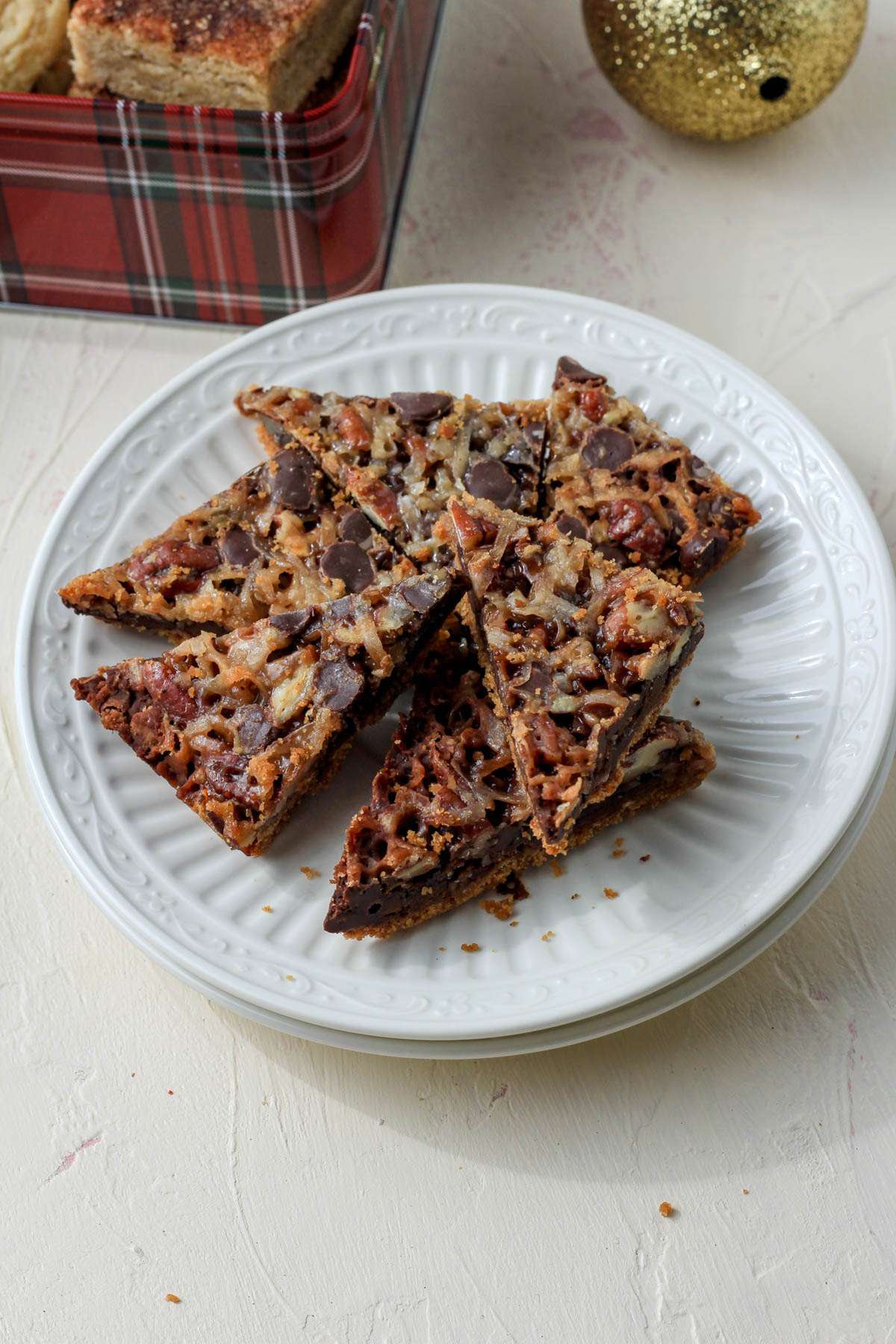 A stack of white plates topped with magic cookie bar triangles.