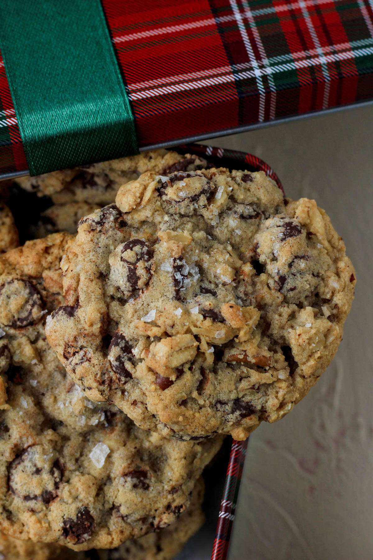 Cowboy cookies in a red and green tin next to a red and green lid.