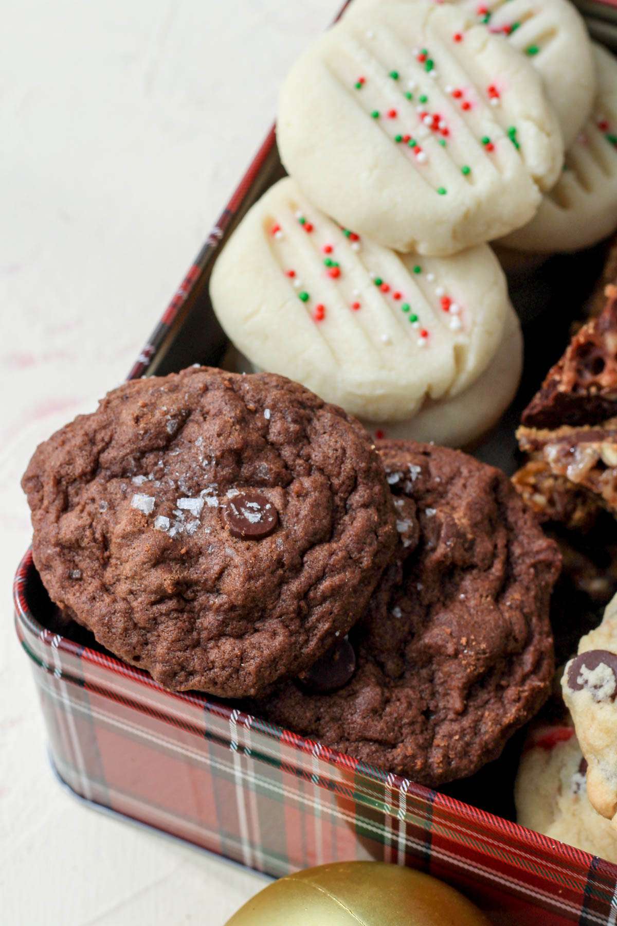 The bottom left corner of the cookie tin with chocolate chocolate chip cookies.
