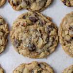 A close up of a dairy-free cowboy cookie on a tan background.