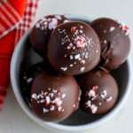 A small white bowl filled with peppermint Oreo truffles topped with crushed peppermint.
