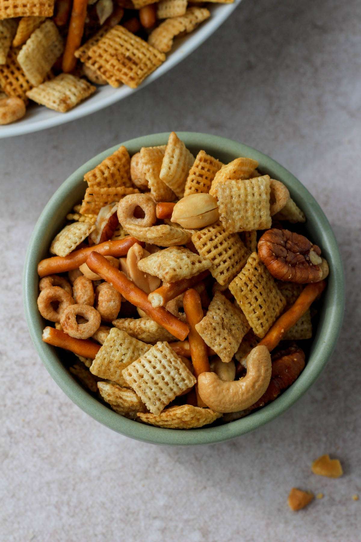 A small green bowl filled with dairy-free Texas trash with a white bowl in the back left.