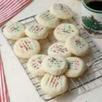 A close up of a wire cooling rack topped with vegan whipped shortbread cookies.