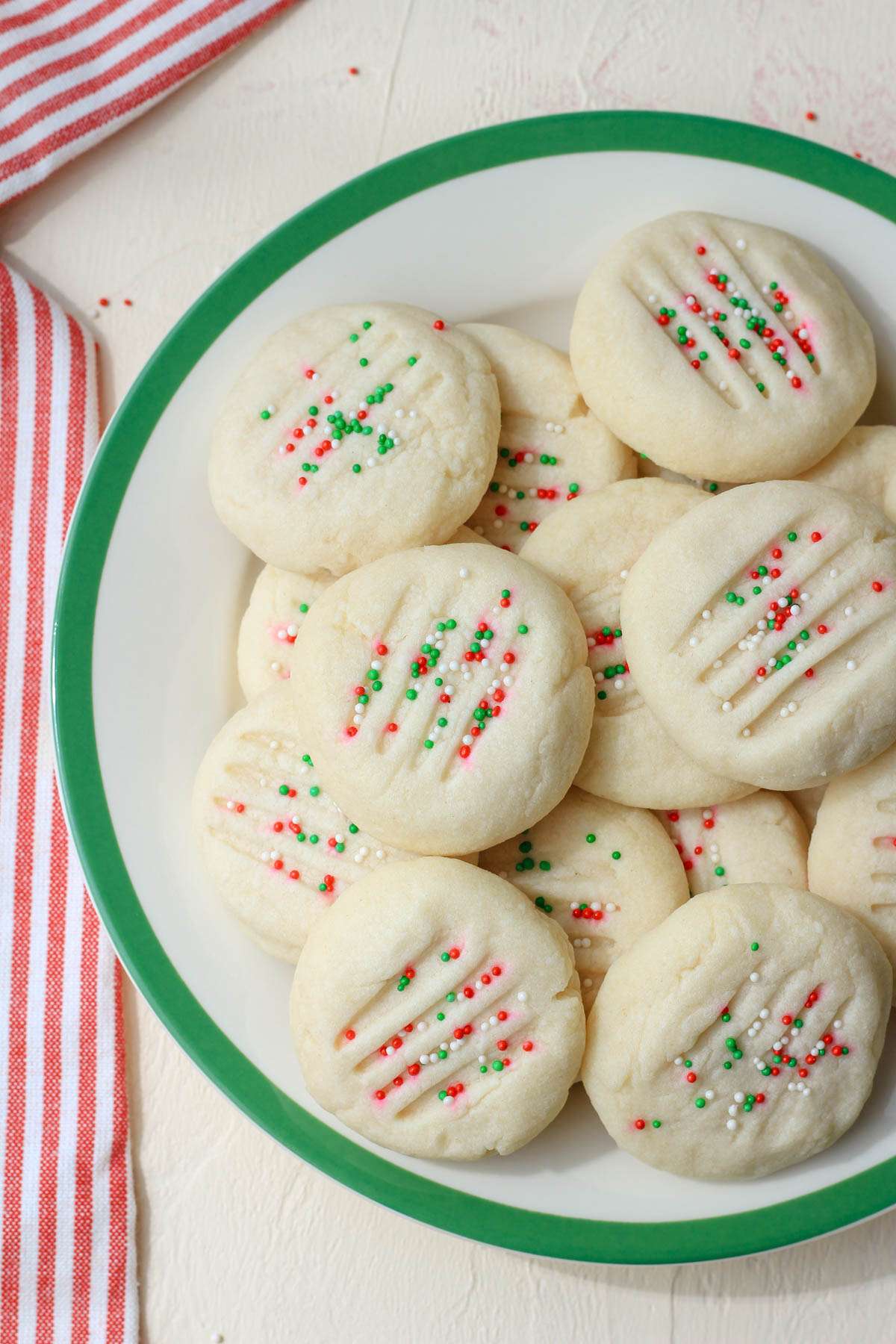 A top down picture of a white and green plate with whipped vegan shortbread cookies.