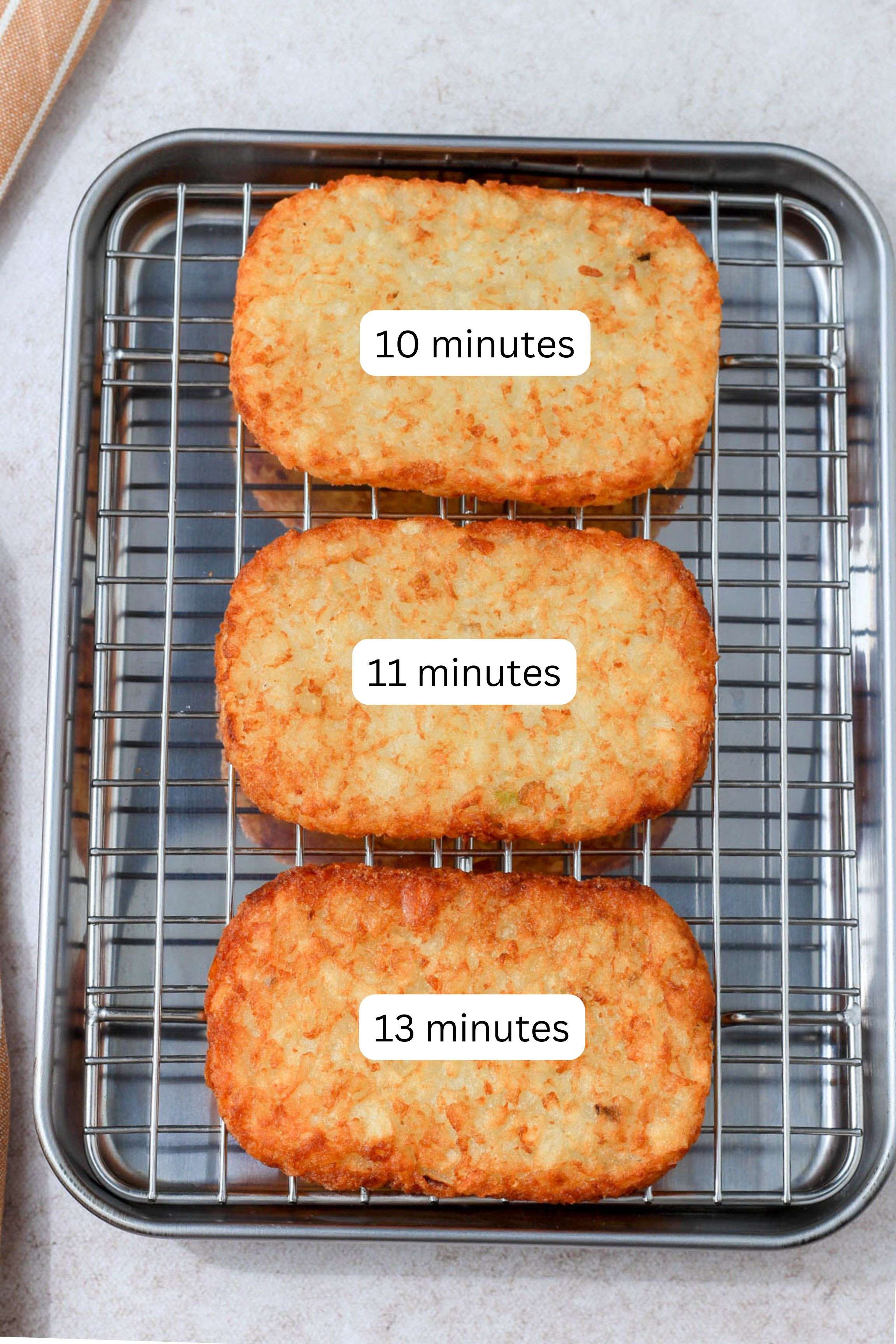 A metal pan with a wire cooling rack with three air fried hash brown patties with a cooking time listed on each hash brown based on how long it took to cook them in the air fryer.