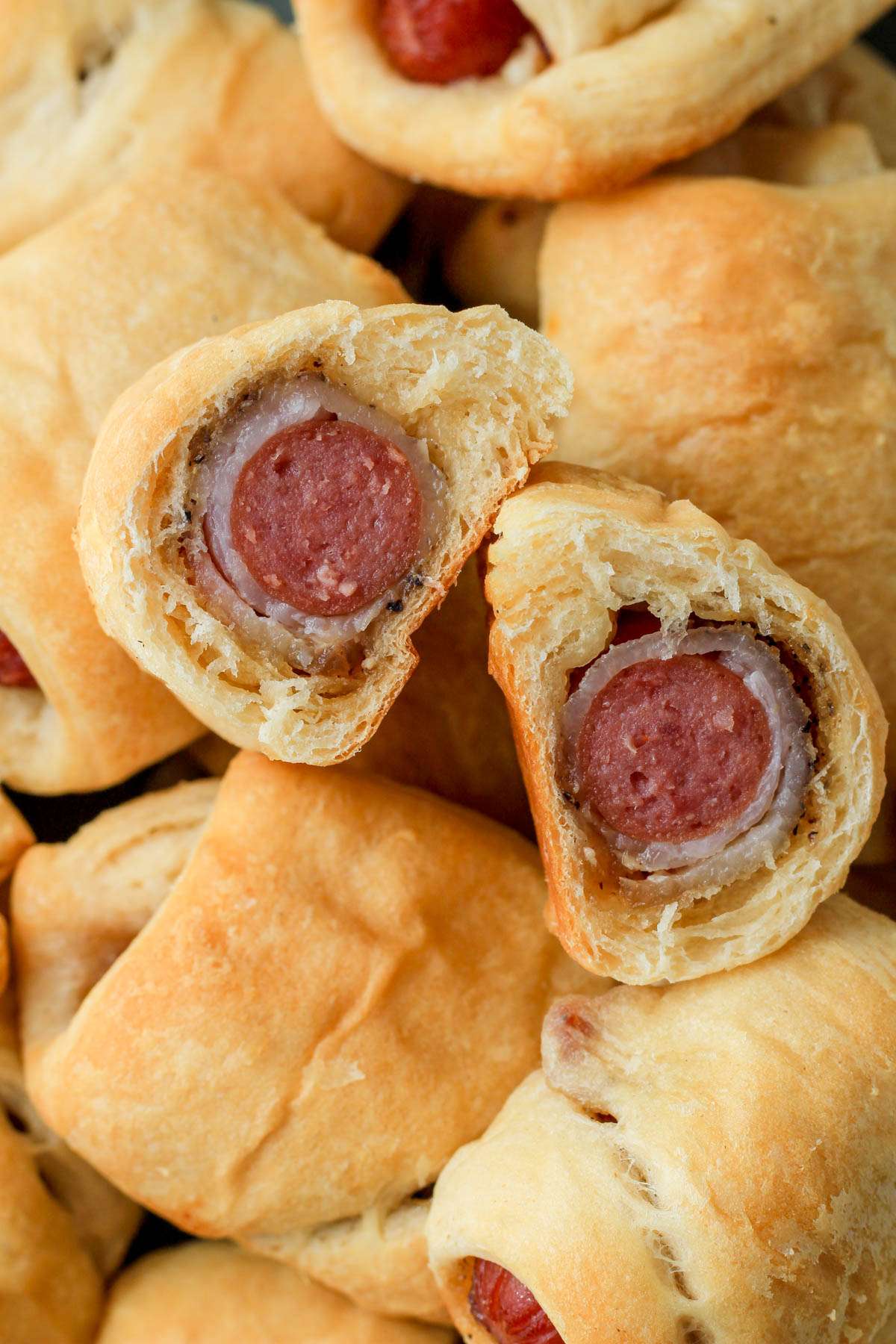 A bacon wrapped pig in a blanket cut in half to show the the inside.