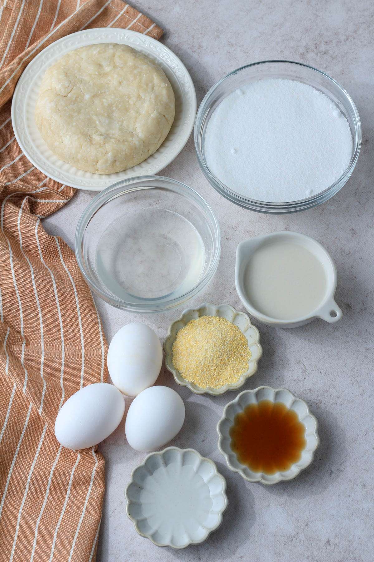 Ingredients for dairy-free chess pie on a tan counter with a rust colored dish towel to the left.