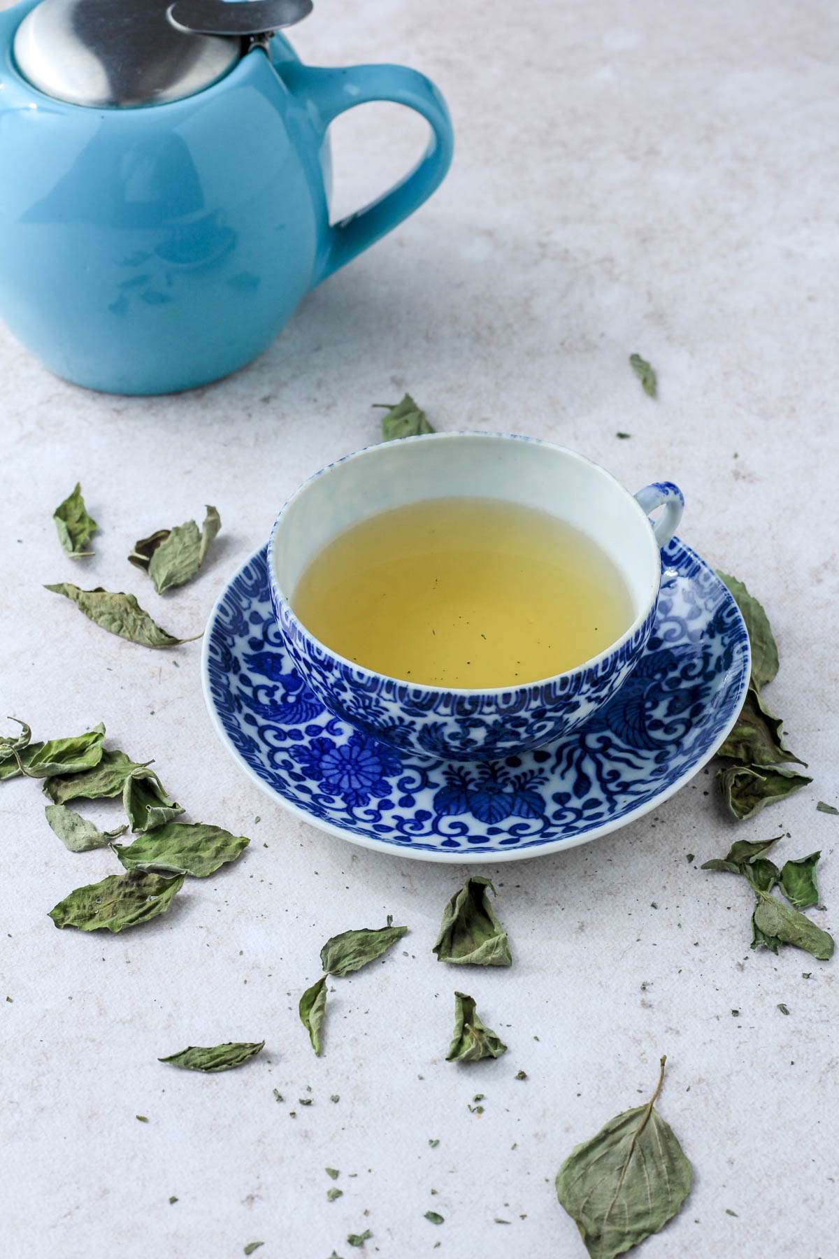 A blue and white tea cup with dried basil tea.