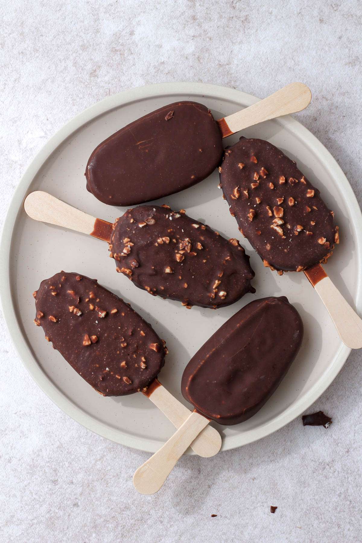 A cream plate with five non-dairy ice cream bars spread around.