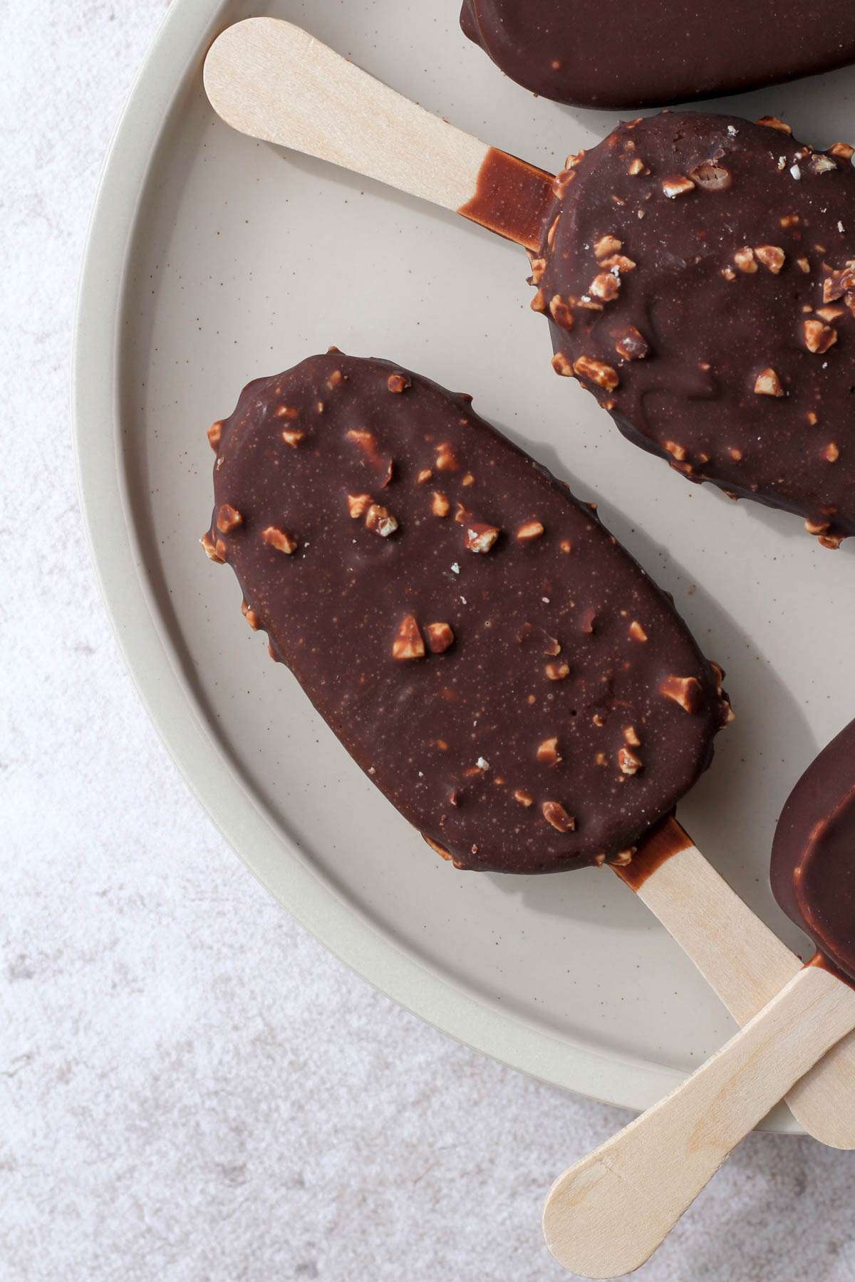 A cream plate with a So Delicious Mocha Almond Fudge dairy free ice cream bar on a cream plate.