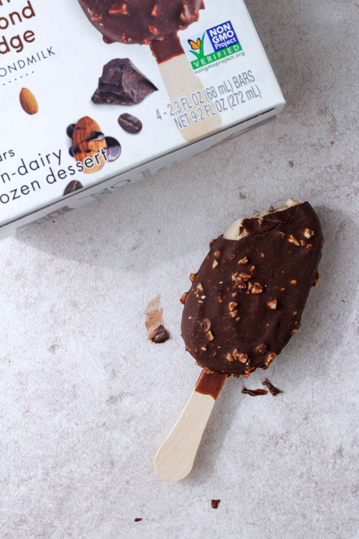 A tan counter with a mocha almond fudge non-dairy ice cream bar with a bite missing next to the dessert box.