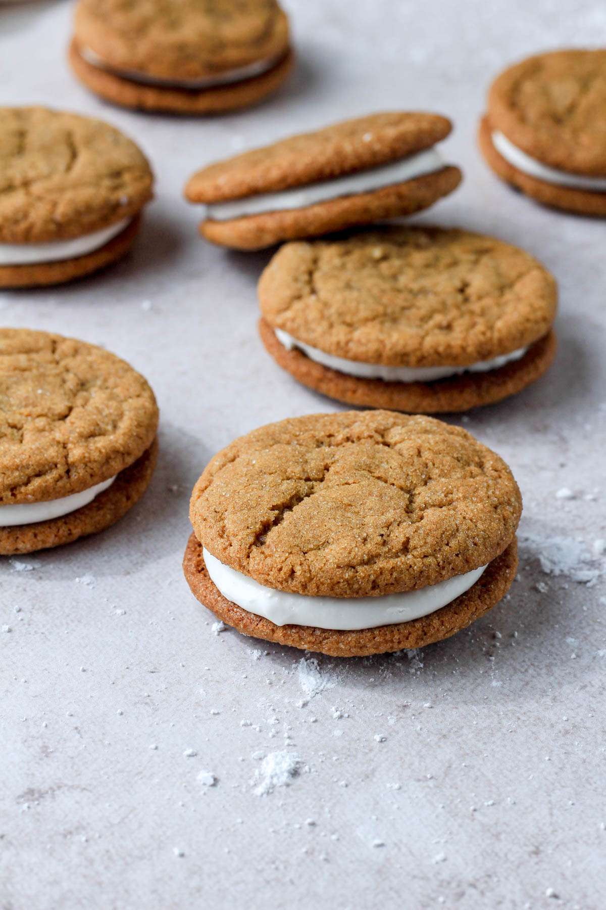 Sift ginger cookie sandwiched with marshmallow cream icing scattered on a cream counter.