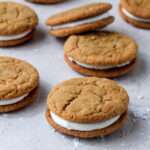 An arrangement of soft ginger cream pie cookies on a tan counter dusted with powdered sugar.