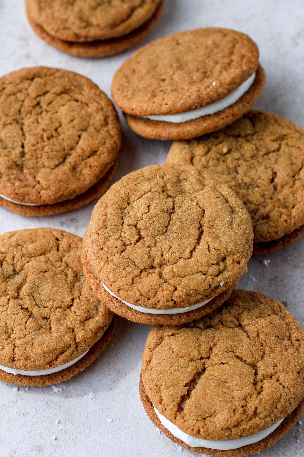 A top down image of a pile of dairy-free soft ginger cookies with marshmallow cream filling.