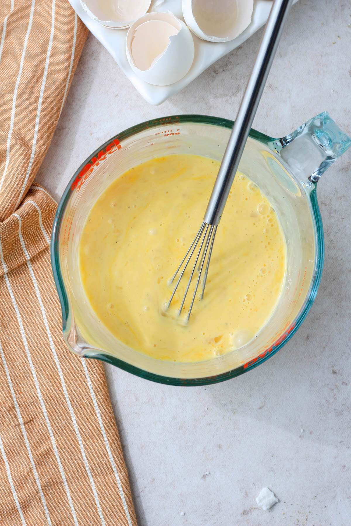 A large liquid measuring cup with the egg mixture for spinach and feta egg bites mixed together.