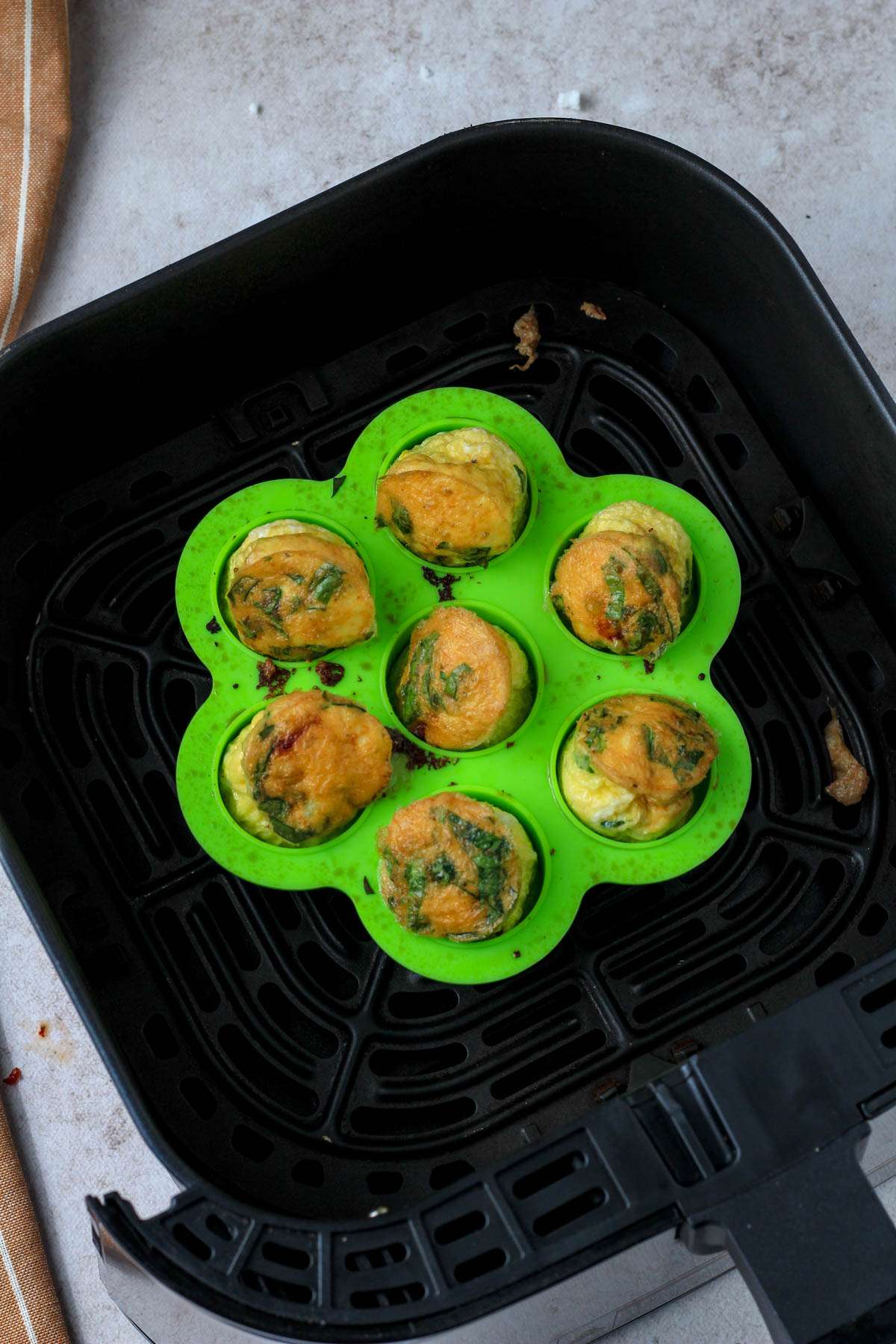 A green egg bites mold with spinach, feta, and sun dried tomato egg bites after cooking in the air fryer.