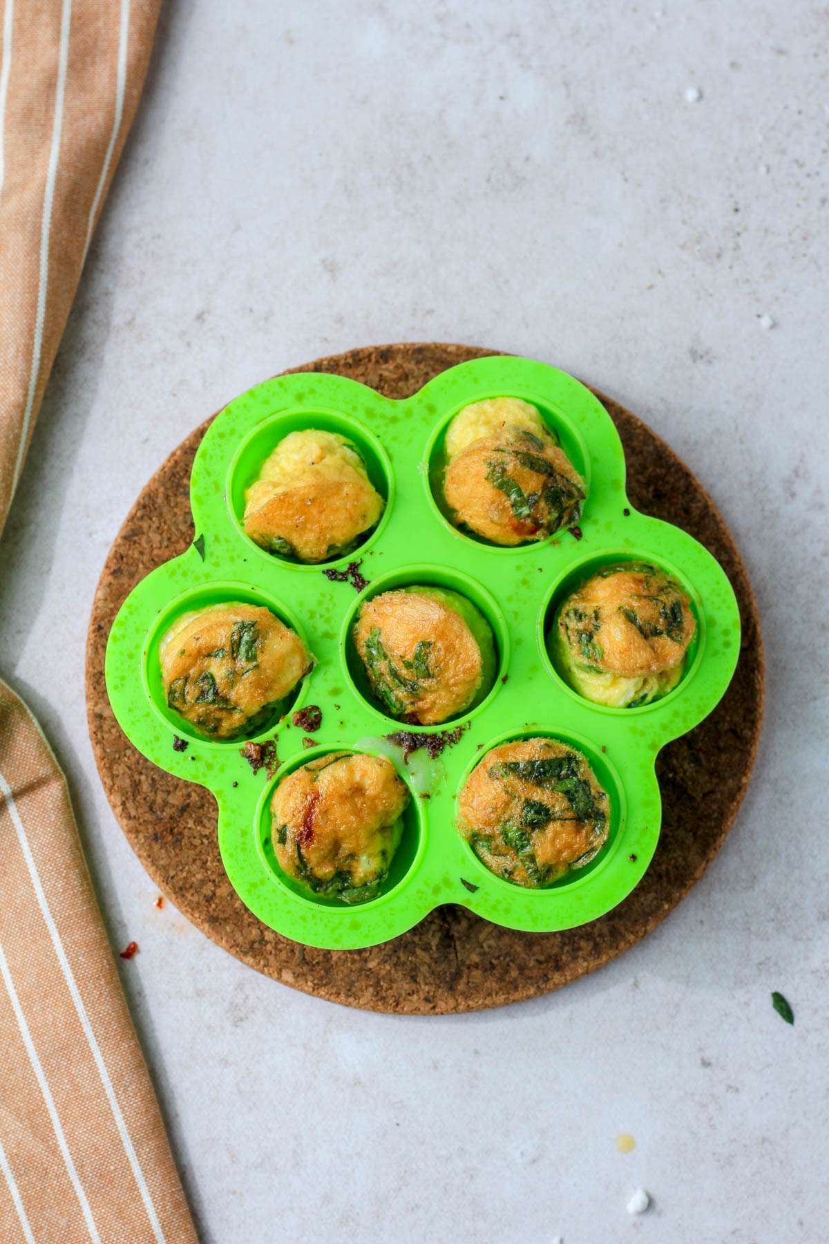 Air fried spinach, feta, and sun dried tomato egg bites in a green egg bites mold before flipping over.