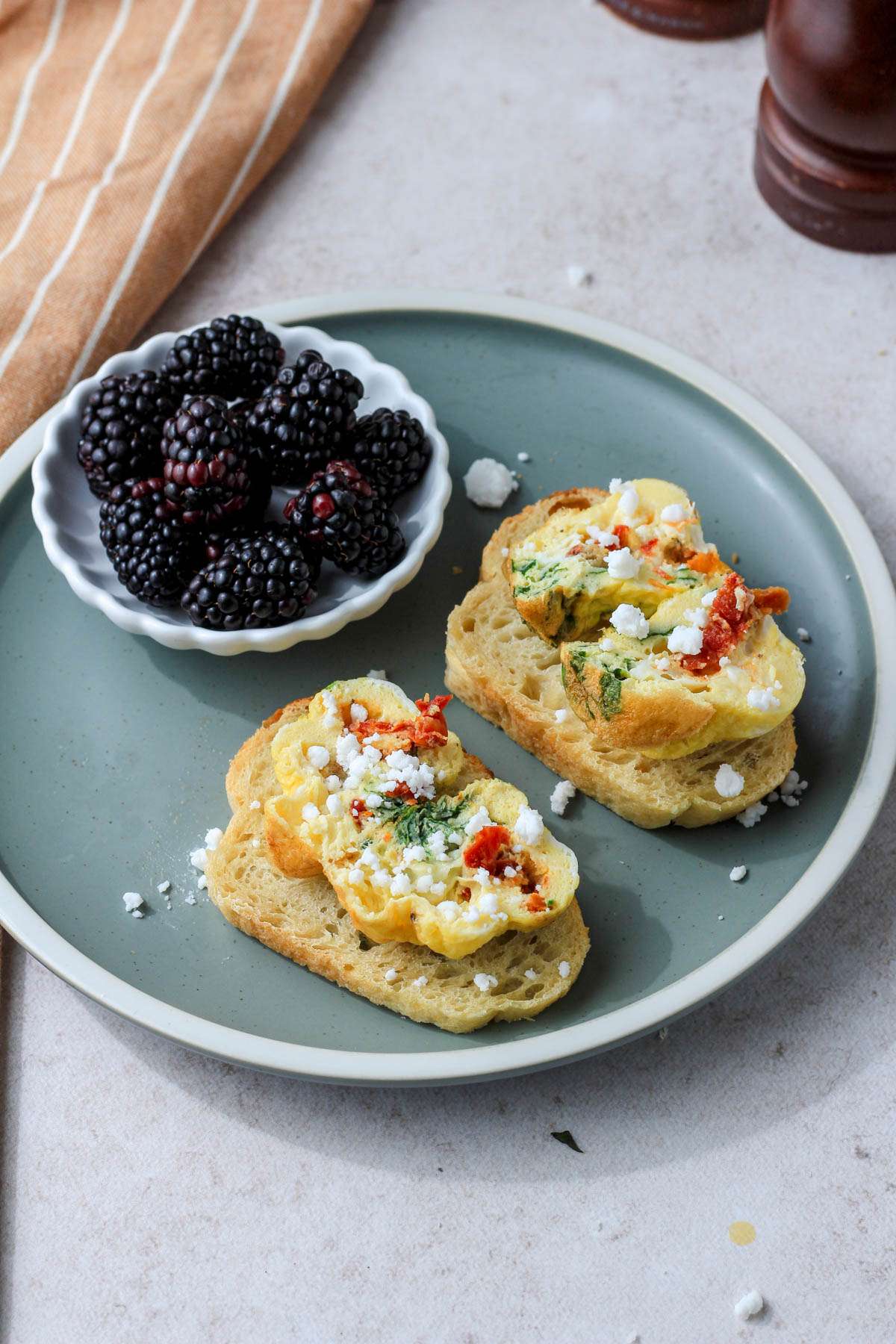 Two slices of toast topped with cut open spinach and feta egg bites topped with extra vegan feta.
