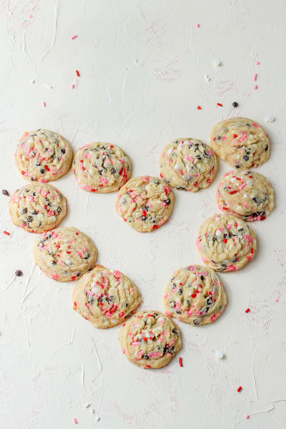 A cream counter with valentines day chocolate chip cookies arranged in a heart shape.