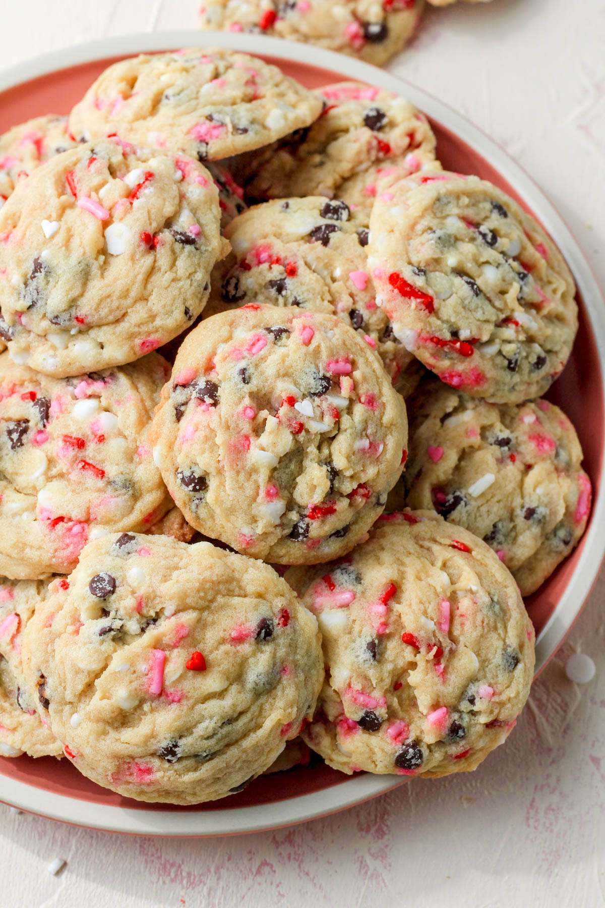 A pink plate with a cream rim topped with dairy-free valentines day chocolate chip cookies.