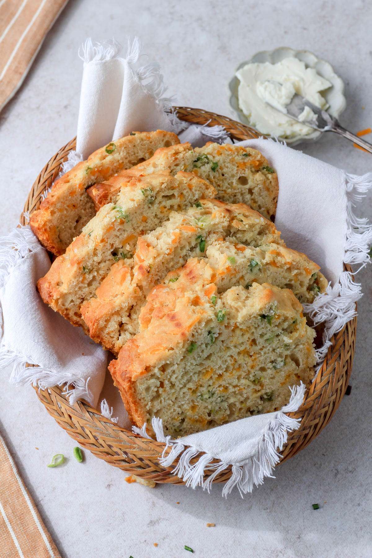 A small bread basket lined with a white cloth topped with slices of beer bread.